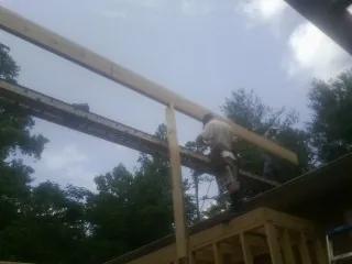 Carpenter setting a ridge beam over a new addition frame — Ice Dam Removal by Roofing Brothers in Mc Kean