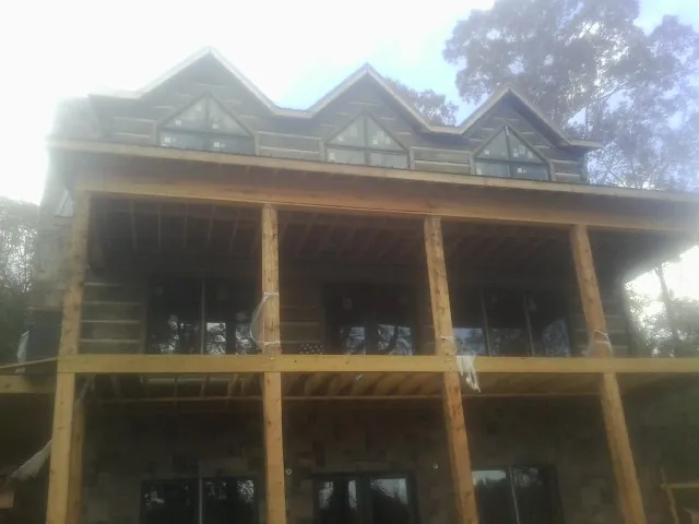 Dormers and porch framing on a large log home under construction — Roof Coating work by our crew in Mc Kean