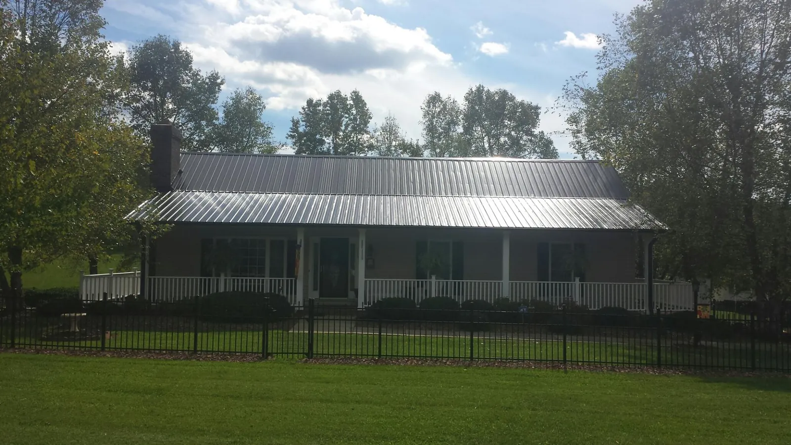 Gray metal roof on a brick ranch with a full width front porch — Gutter Guard Installation work by our crew in Mc Kean