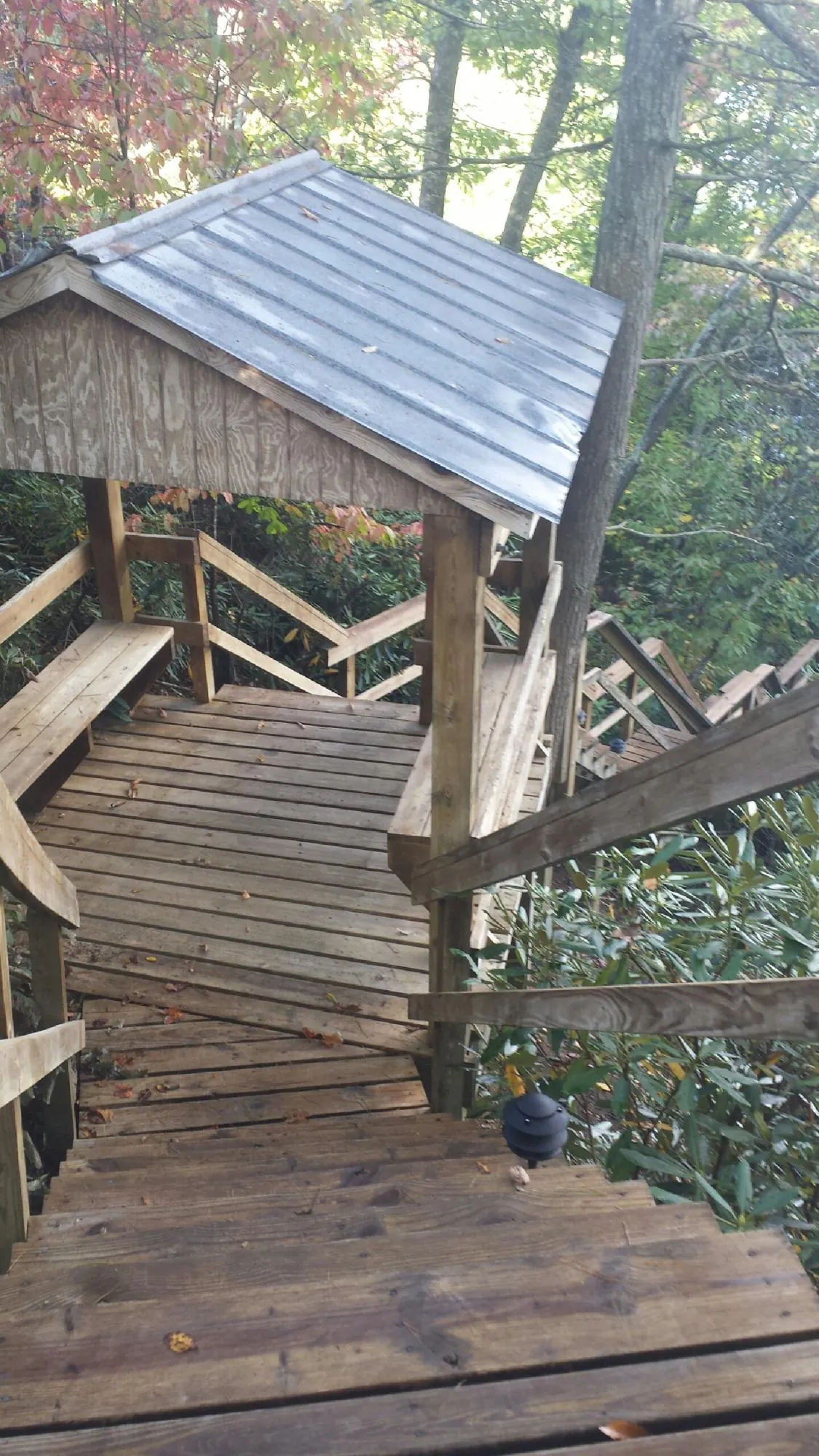Metal roofed shelter over wooden steps on a wooded walkway — Skylight Repair & Installation work by our crew in Mc Kean