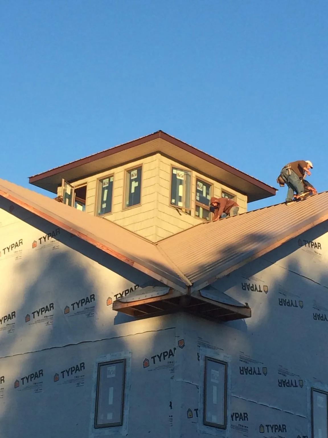 Roofers working around a rooftop cupola on a new metal roof at sunset — Roof Waterproofing in Mc Kean by Roofing Brothers